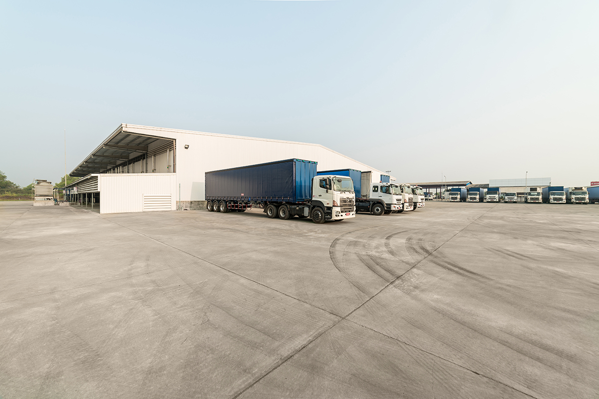 Factory trucks parked near a white building with a clear sky in the background A factory trucks parked near a white building with a clear sky in the background
