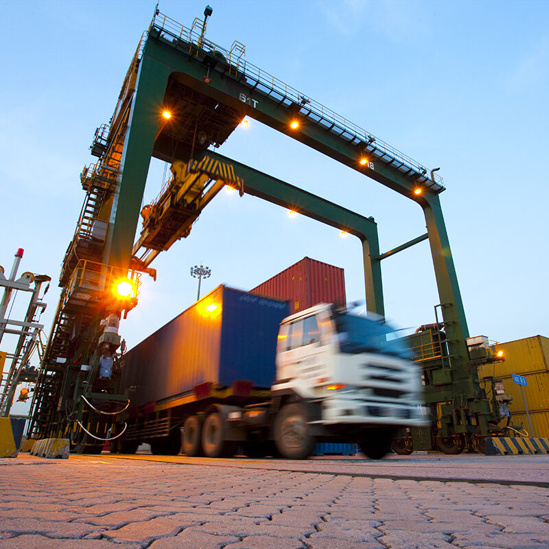 Blurred motion of truck with cargo containers and cranes in a shipping port