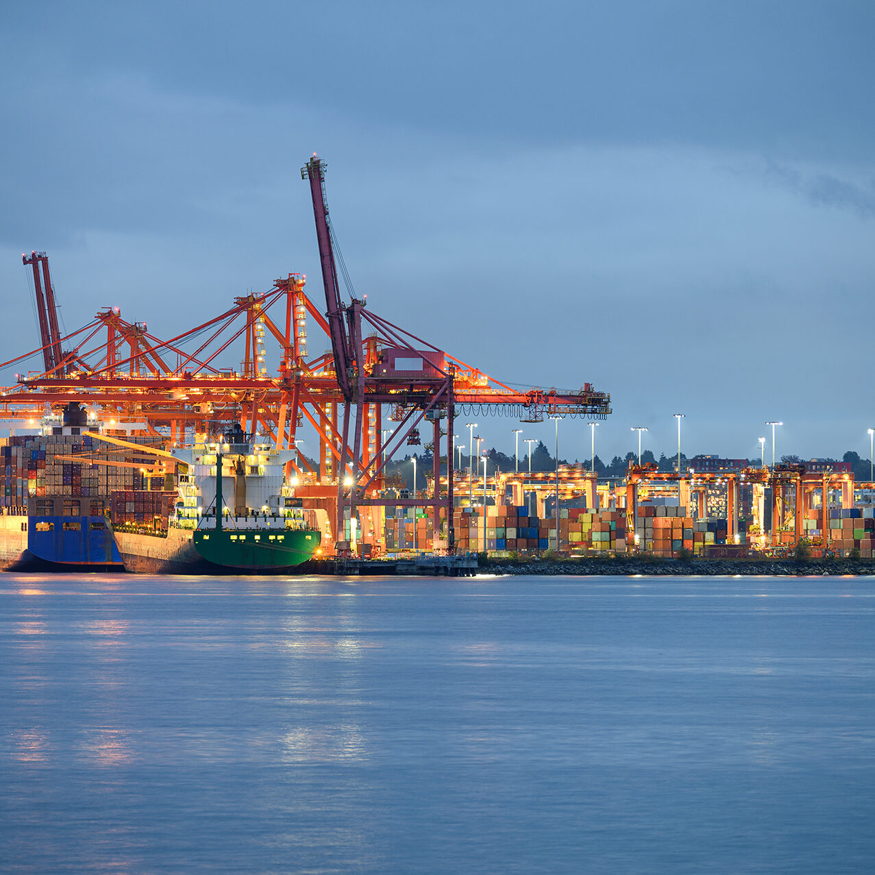 International cargo ship with containers cargo illumination and International cargo ship with containers cargo illumination and gantry cranes at port in dusk